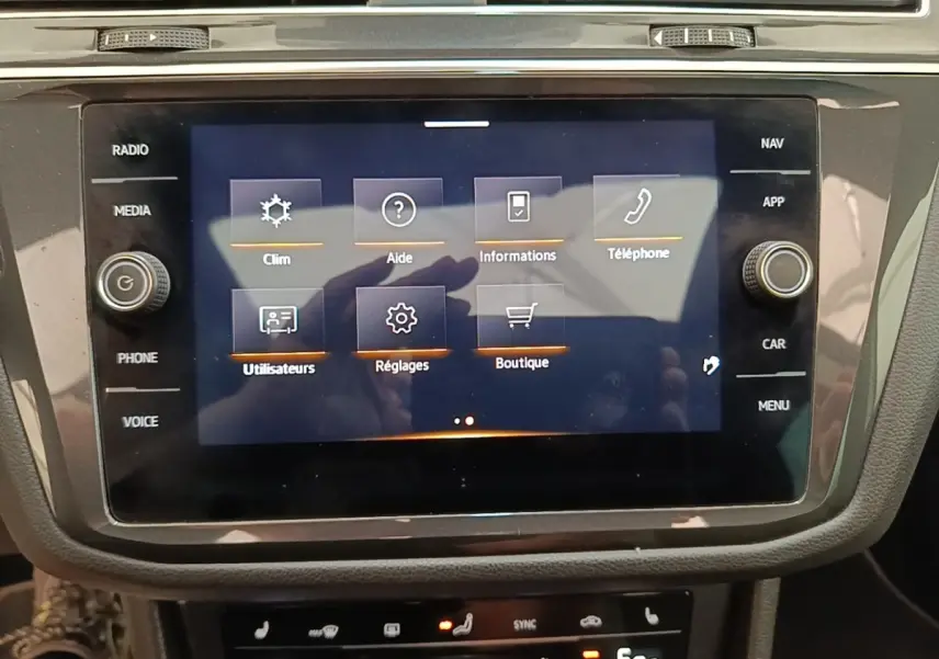 Écran tactile central affichant le menu principal du système multimédia dans un Volkswagen Tiguan blanc 2023.