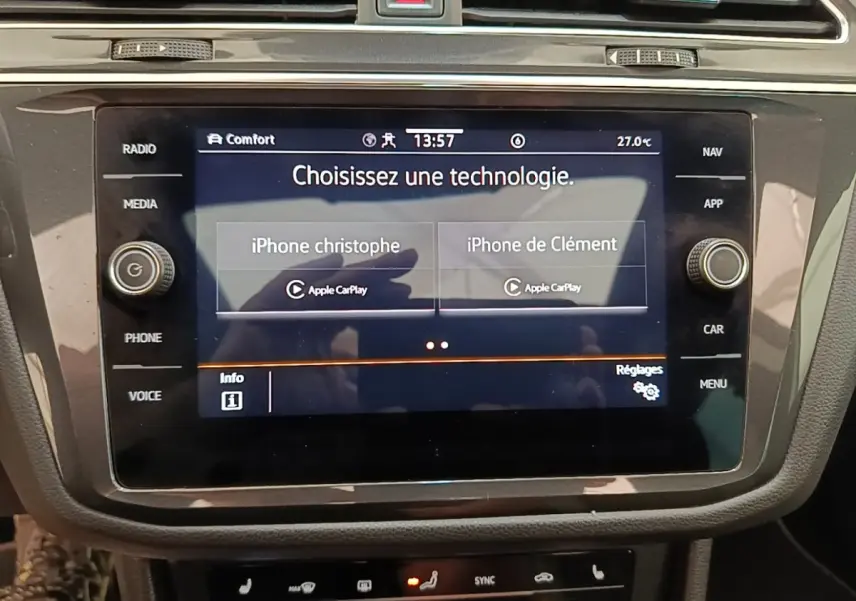 Écran tactile central du Volkswagen Tiguan blanc 2023 montrant la connexion Apple CarPlay avec deux iPhones.