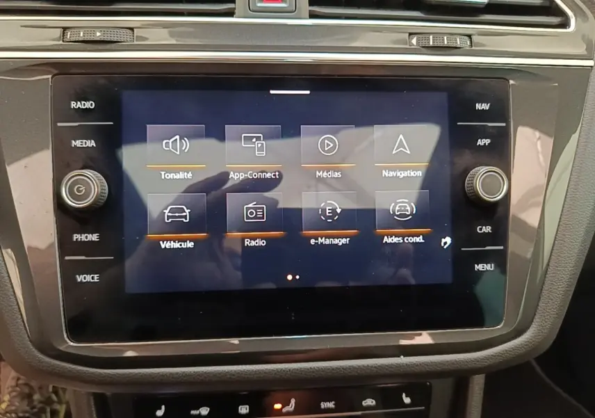 Écran tactile central du Volkswagen Tiguan blanc 2023 affichant le menu multimédia et navigation.