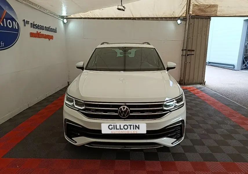 Vue avant d'un Volkswagen Tiguan blanc 2023 en version R-Line, avec phares LED allumés dans un garage.