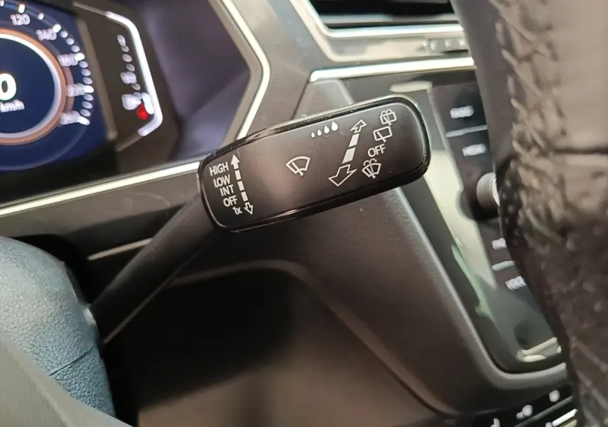 Gros plan sur la commande des essuie-glaces du Volkswagen Tiguan 1.4 eHybrid 2023, intérieur noir et tableau de bord digital.