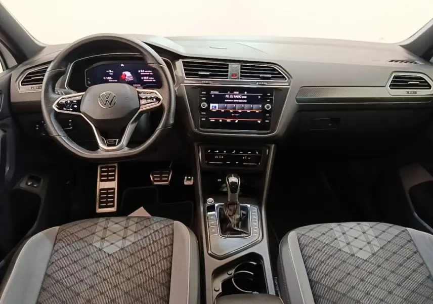 Vue intérieure avant du Volkswagen Tiguan 1.4 eHybrid 2023, tableau de bord noir avec écran tactile central et volant multifonctions.