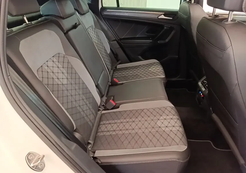 Vue intérieure côté droit des sièges arrière en tissu gris à motifs du Volkswagen Tiguan blanc 2023 hybride rechargeable.