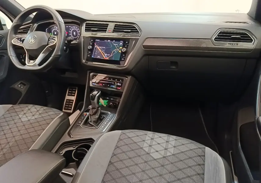 Intérieur avant du Volkswagen Tiguan blanc 2023, vue côté passager, tableau de bord avec écran tactile et volant multifonctions.