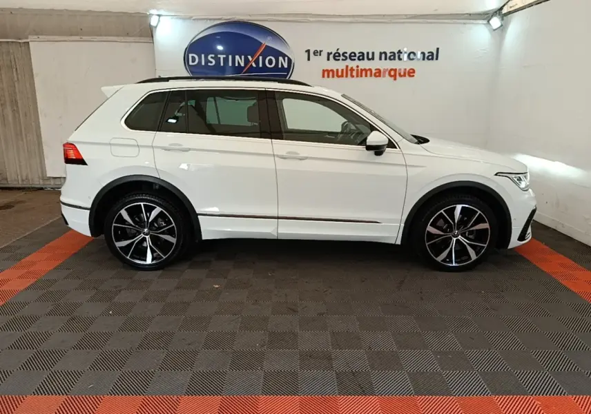 Vue latérale droite d'un Volkswagen Tiguan blanc 1.4 eHybrid 245 DSG6 R-Line dans un showroom intérieur.