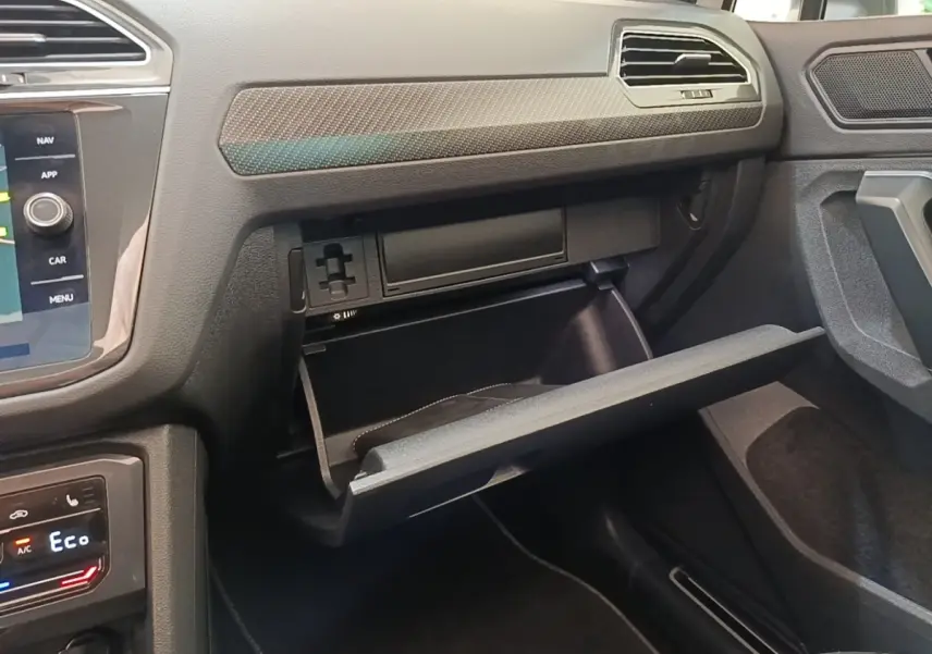 Intérieur Volkswagen Tiguan 2023 blanc, vue côté passager sur la boîte à gants ouverte et tableau de bord moderne.