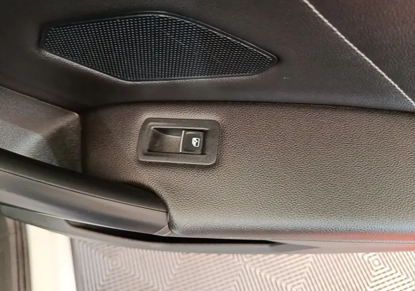 Détail du bouton d'ouverture électrique du coffre sur la garniture intérieure noire du Volkswagen Tiguan 1.4 eHybrid 2023.