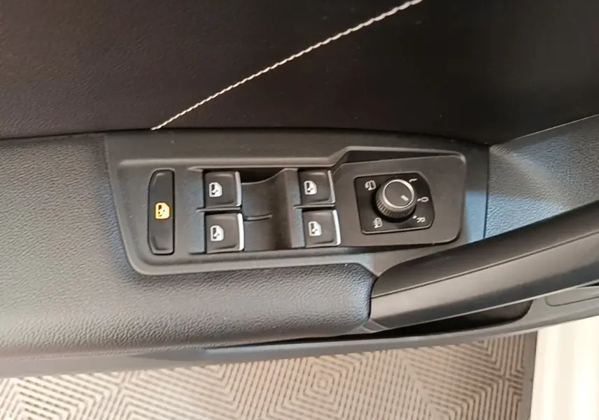 Gros plan sur les commandes des vitres et rétroviseurs côté conducteur du Volkswagen Tiguan blanc 2023.