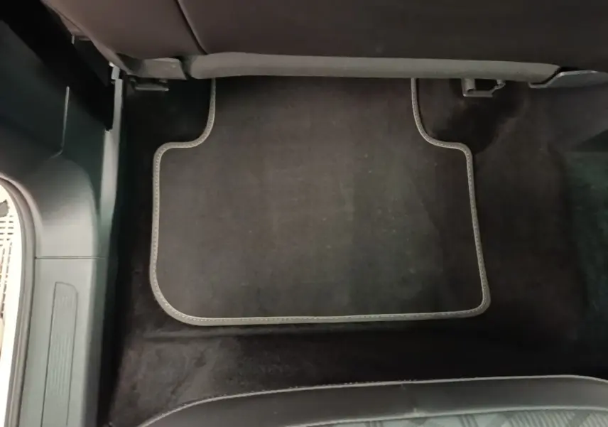 Tapis de sol noir avec surpiqûres grises sous siège arrière d’un Volkswagen Tiguan blanc, vue intérieure au sol.