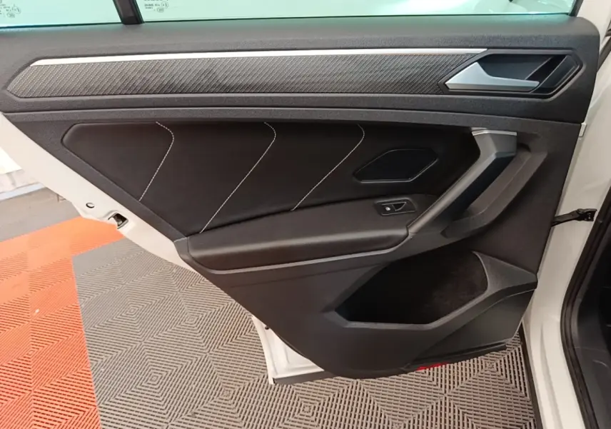Vue rapprochée de la porte arrière droite blanche du Volkswagen Tiguan 1.4 eHybrid 2023 avec garniture noire et surpiqûres blanches.