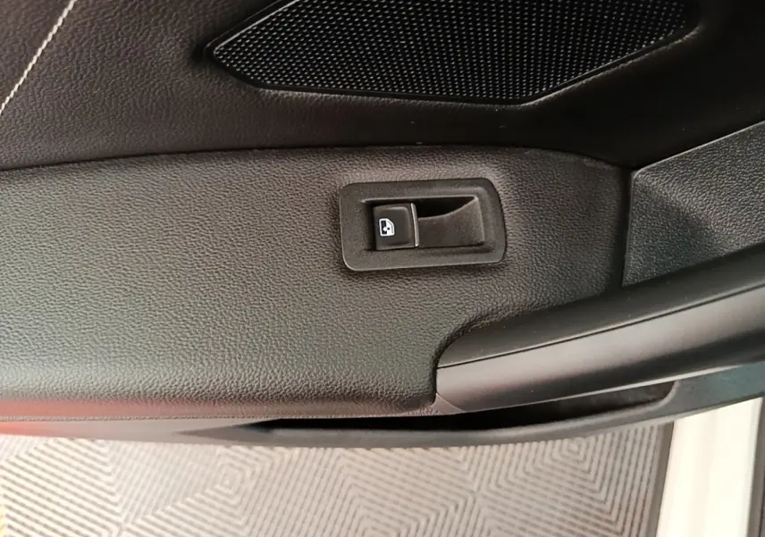 Gros plan sur la commande de verrouillage de porte intérieure noire du Volkswagen Tiguan blanc, côté conducteur.