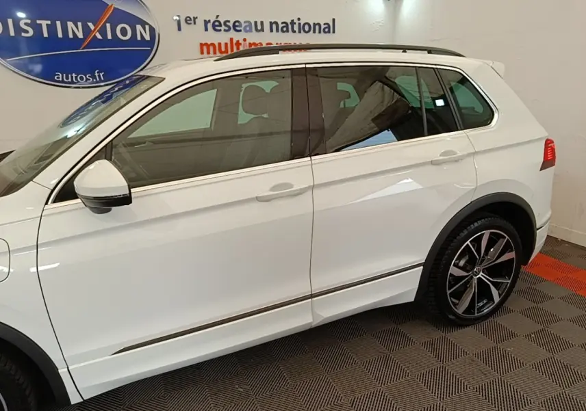 Profil côté gauche d’un Volkswagen Tiguan blanc 2023 avec jantes alliage noires et rétroviseurs électriques.