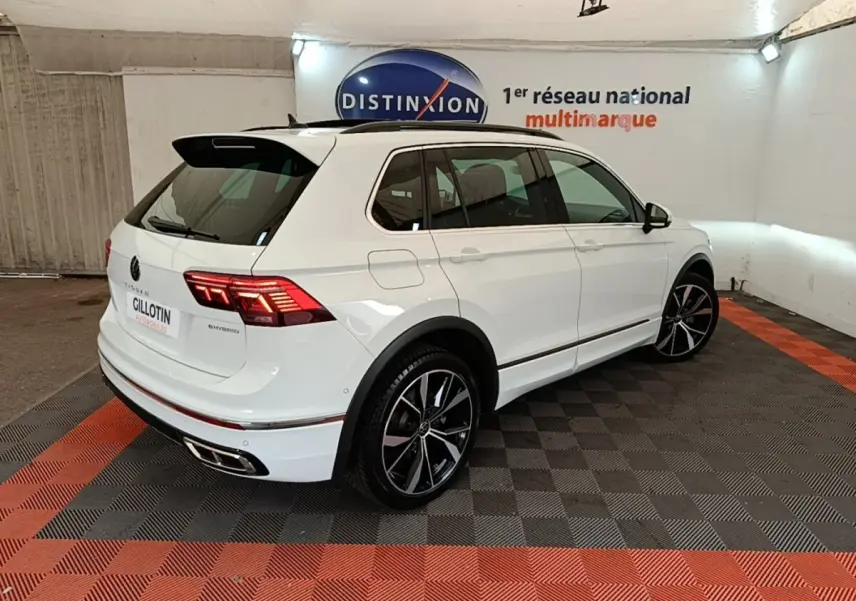 Volkswagen Tiguan blanc 1.4 eHybrid 245 DSG6 R-Line vu 3/4 arrière droit avec jantes noires et feux LED allumés.