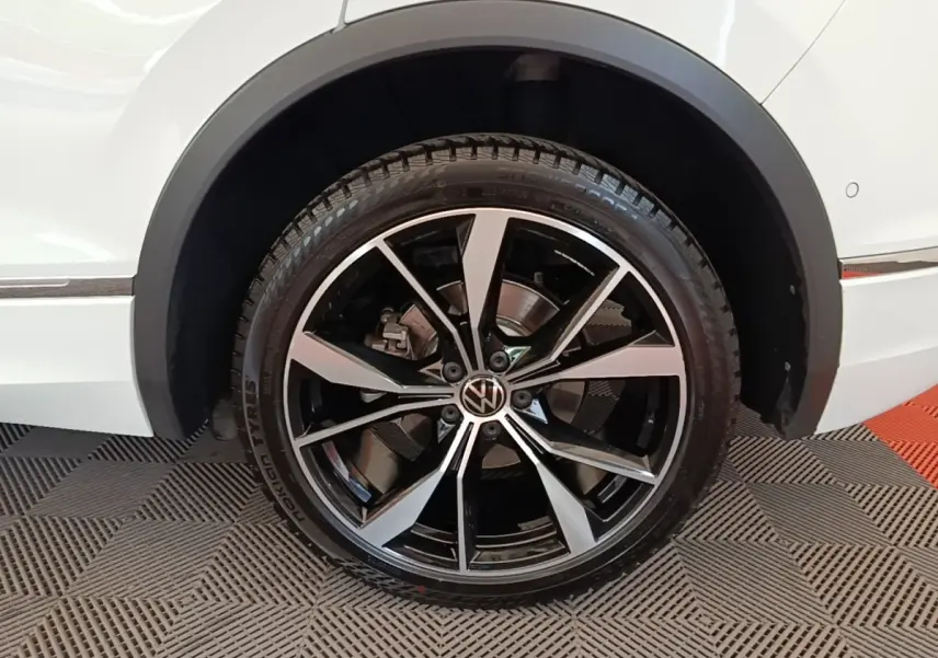 Gros plan sur la roue avant droite noire et argentée du Volkswagen Tiguan blanc 1.4 eHybrid 2023 R-Line.
