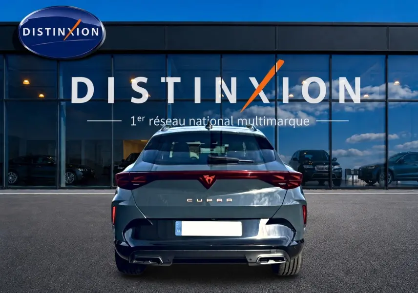 Vue arrière d'une CUPRA Formentor bleu fjord 2026 avec feux LED et double sortie d'échappement, stationnée devant un showroom.
