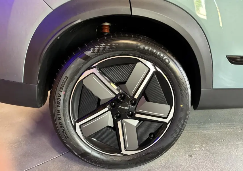 Gros plan sur la roue avant gauche du JAECOO J7 gris olive, mettant en valeur la jante alliage 19 pouces au design moderne.