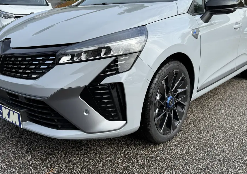 Vue 3/4 avant droit d'une Renault Clio V gris Rafale avec jantes noires et badge Alpine sur l'aile avant.