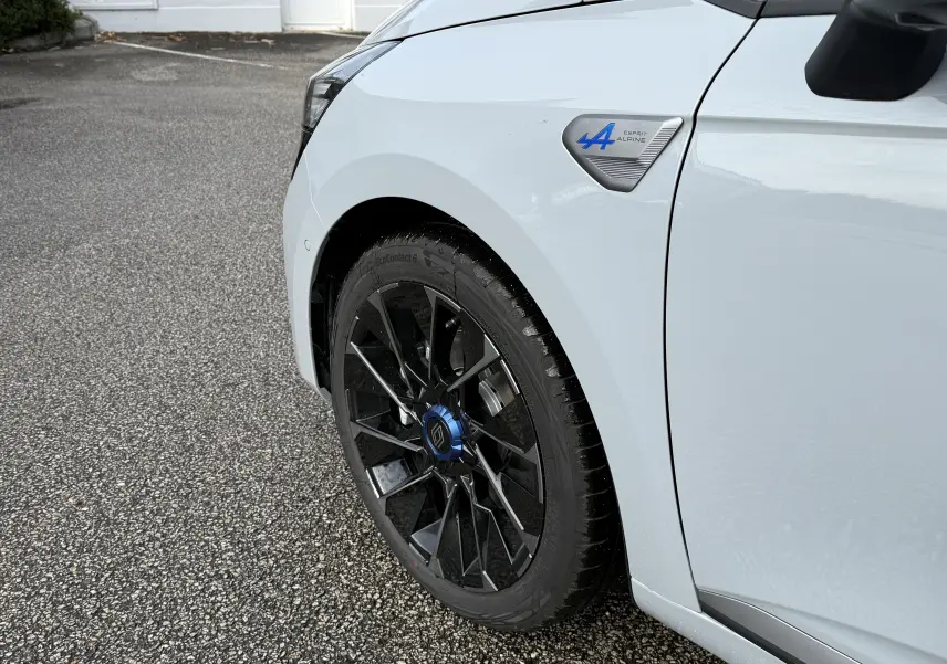 Gros plan sur la roue avant gauche et l'aile gris rafale d'une Renault Clio V Esprit Alpine 2025 avec logo bleu distinctif.