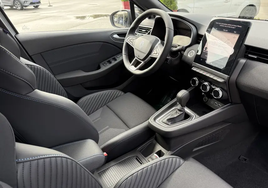 Intérieur de la Renault Clio V 1.6 E-TECH gris Rafale, vue côté conducteur, volant multifonction et écran tactile vertical.