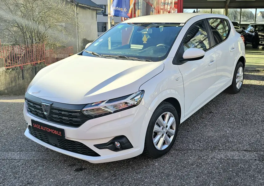 Dacia Sandero III blanc glacier vue 3/4 avant droit, avec calandre noire et jantes alliage argentées.