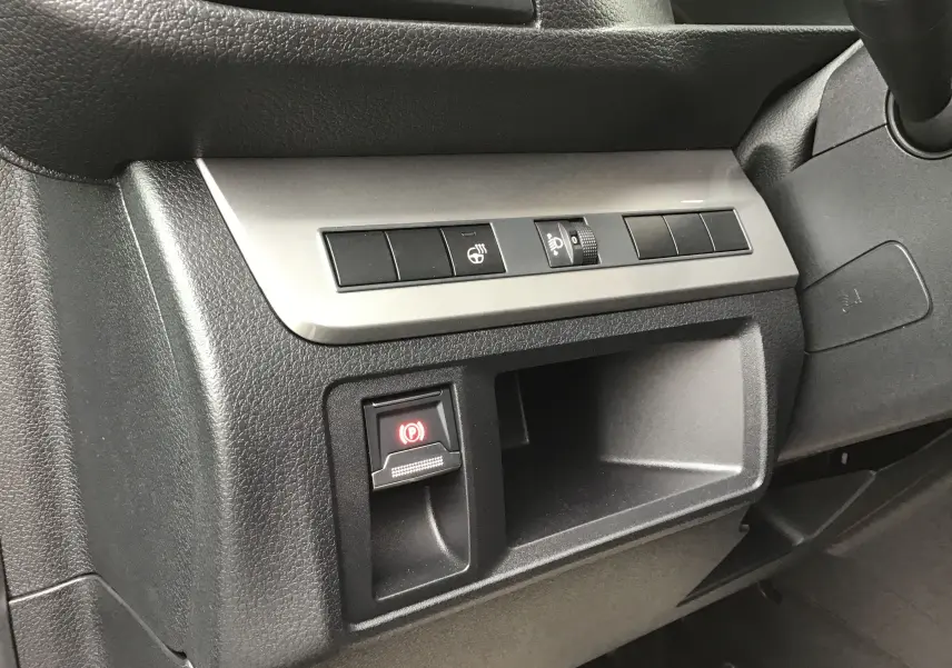 Gros plan sur la console côté conducteur du Peugeot Expert gris titane, montrant les commandes d’éclairage et le frein à main électrique.