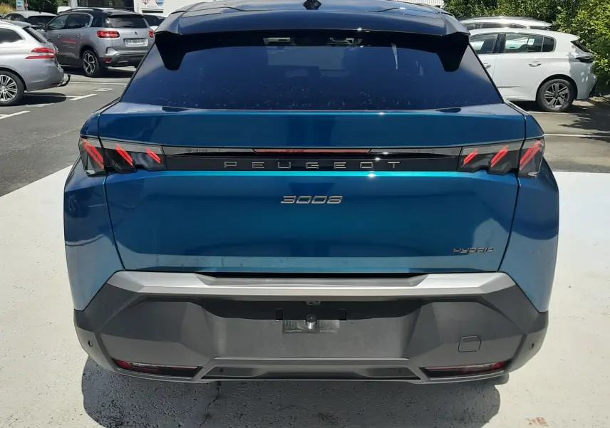 Vue arrière d'un Peugeot 3008 bleu obsession 2026 avec feux arrière à griffes rouges et logo hybride visible.
