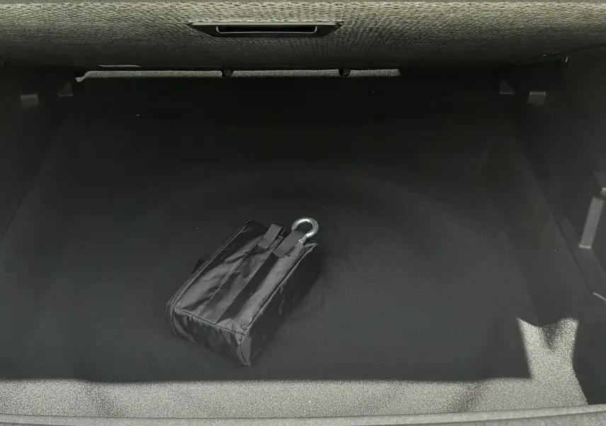 Vue plongeante sur le coffre vide d’un Peugeot 3008 1.2 Hybrid 145ch GT 2026, avec un kit de secours noir visible.