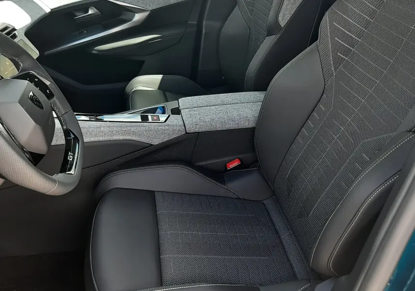 Vue intérieure côté conducteur du Peugeot 3008 1.2 Hybrid 145ch GT 2026 avec sièges tissu et cuir noir, volant compact GT.