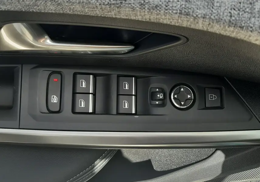 Gros plan sur les commandes de lève-vitres et rétroviseurs côté gauche de la porte d’un Peugeot 3008 2026.