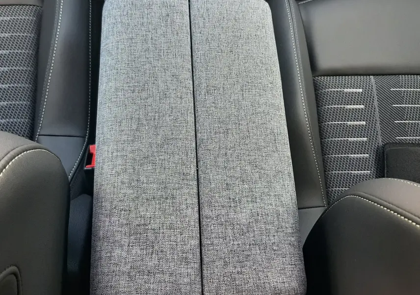 Détail de l'accoudoir central en tissu gris et cuir noir à l'intérieur du Peugeot 3008 Hybrid 145ch GT 2026.