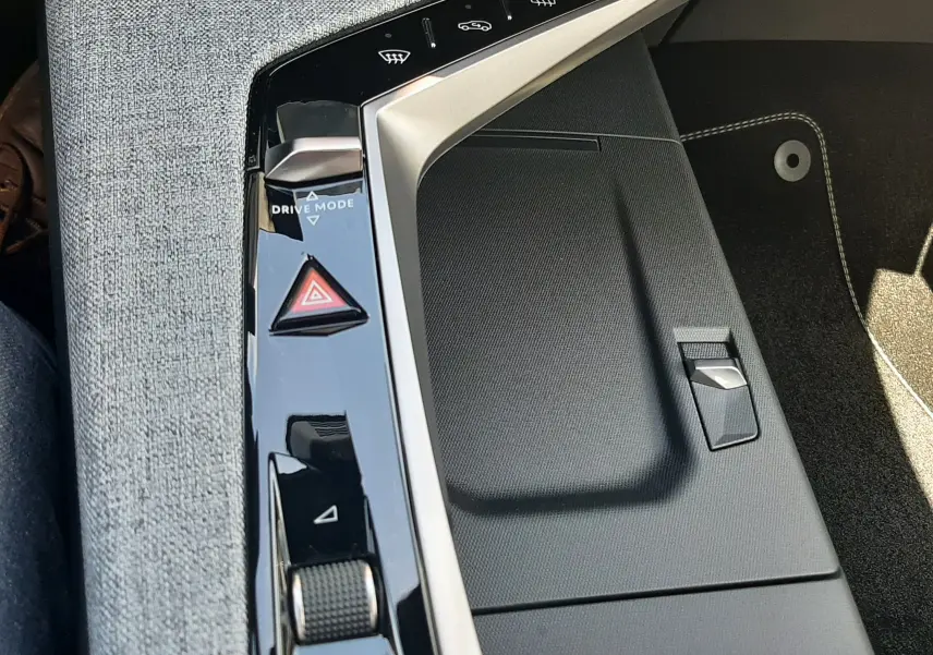 Détail de la console centrale noire et grise du Peugeot 3008 Hybrid 2026, avec commandes tactiles et molette de réglage.