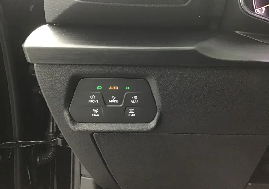 Gros plan sur les commandes d'éclairage et de désembuage côté gauche du tableau de bord noir du CUPRA Leon 2023.