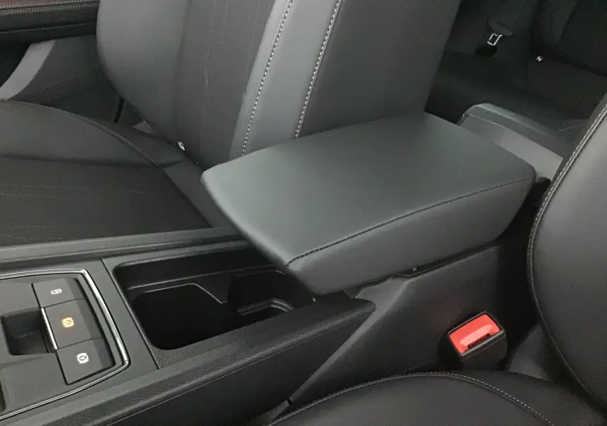 Gros plan sur l'accoudoir central en cuir noir et la console avec commandes électroniques dans l'habitacle d'une CUPRA Leon 2023.