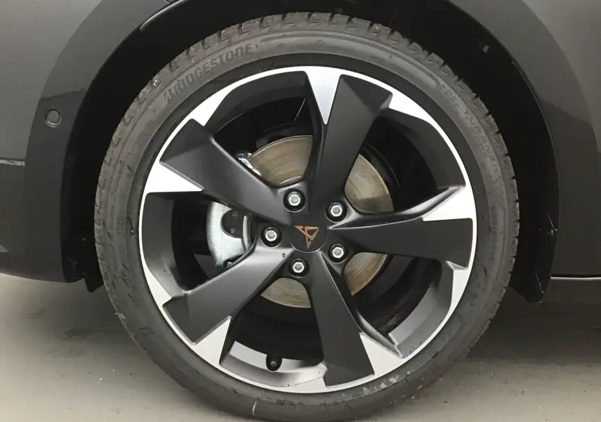 Gros plan sur la jante bi-ton noir et argent avec logo CUPRA sur une roue avant d'une CUPRA Leon noire 2023.