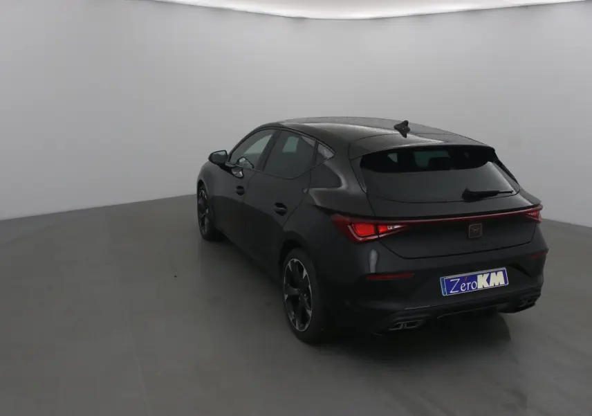 Vue 3/4 arrière droite d'une Cupra Leon noire 2023 avec feux LED et jantes bi-ton 18 pouces dans un studio.