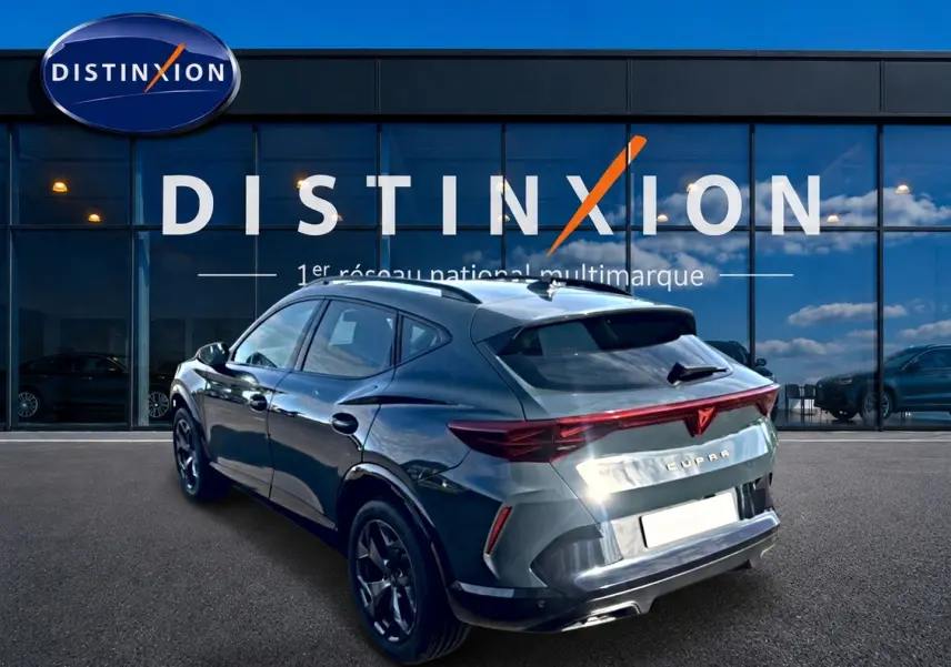 Vue 3/4 arrière droite d’un CUPRA Formentor bleu fjord 2026 avec feux arrière LED et jantes noires devant un showroom Distinxion.