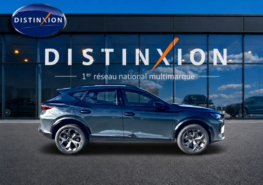 Profil côté gauche d'un CUPRA Formentor 1.5 etsi hybrid bleu fjord avec jantes 18 pouces, devant une vitrine Distinxion.
