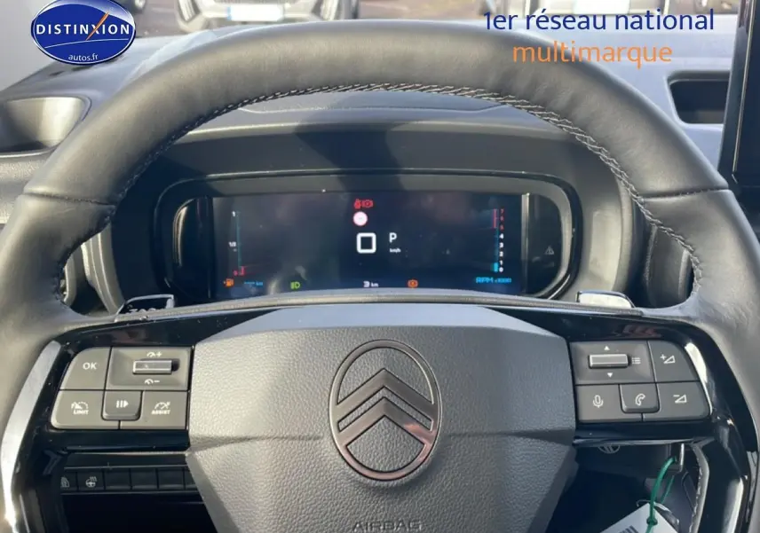 Vue rapprochée du volant cuir multifonction noir avec logo Citroën et tableau de bord numérique du Berlingo gris Artense 2025.