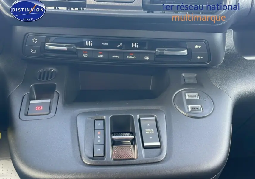 Vue intérieure centrée sur la console centrale du Citroën Berlingo gris, avec commandes clim et boîte auto compacte.