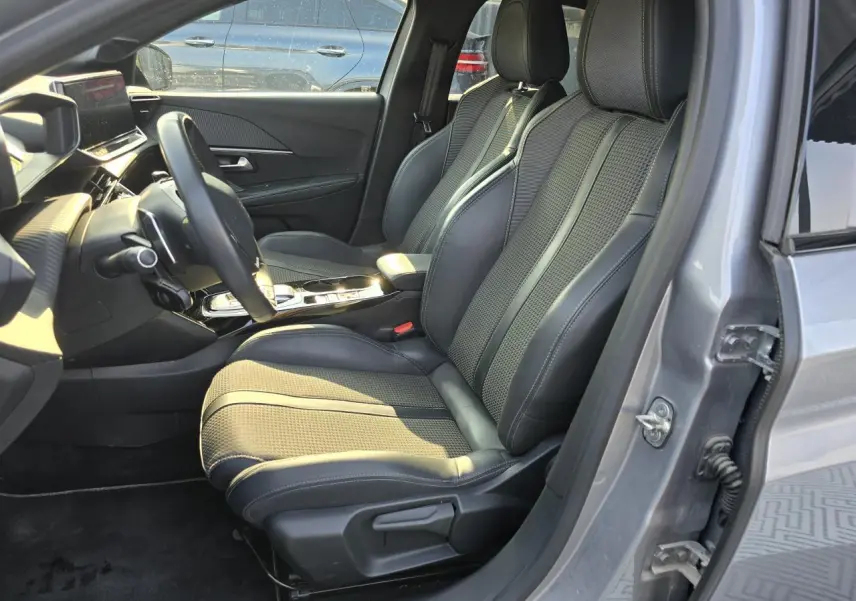 Vue intérieure côté conducteur de la Peugeot 208 grise 2023, sièges avant en tissu et TEP avec surpiqûres contrastées.