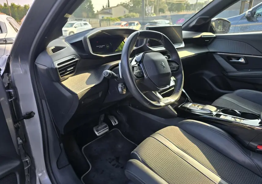 Vue intérieure côté conducteur de la Peugeot 208 grise 2023, avec volant compact et tableau de bord numérique.