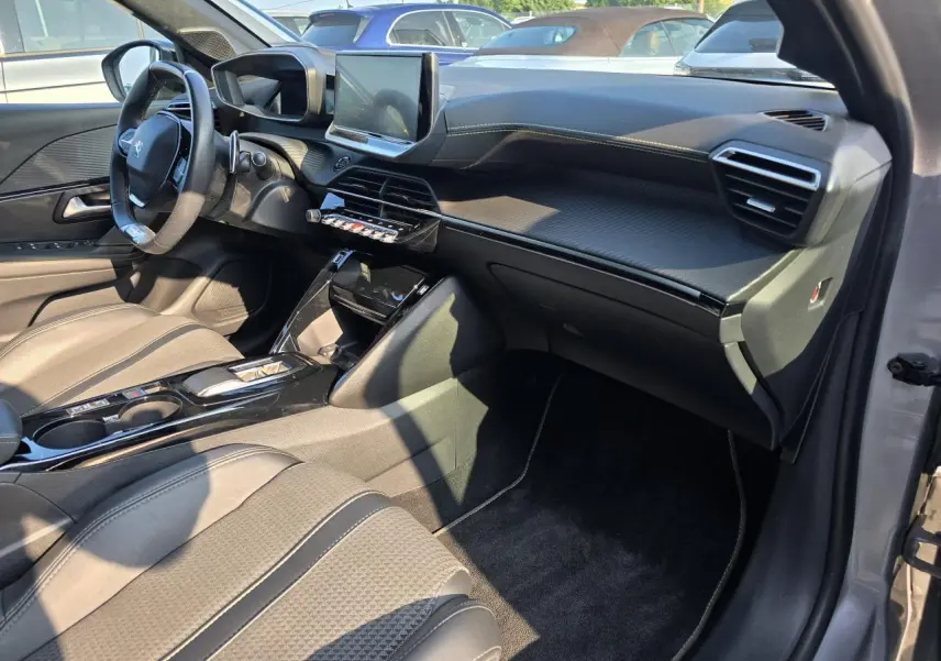 Vue intérieure côté passager de la Peugeot 208 grise 2023, tableau de bord carbone et écran tactile 10 pouces.