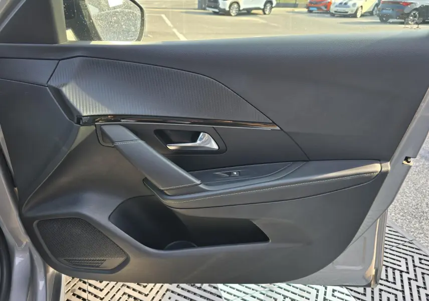Vue côté gauche de la porte avant grise de la Peugeot 208 II avec habillage noir et insert décoratif texturé.