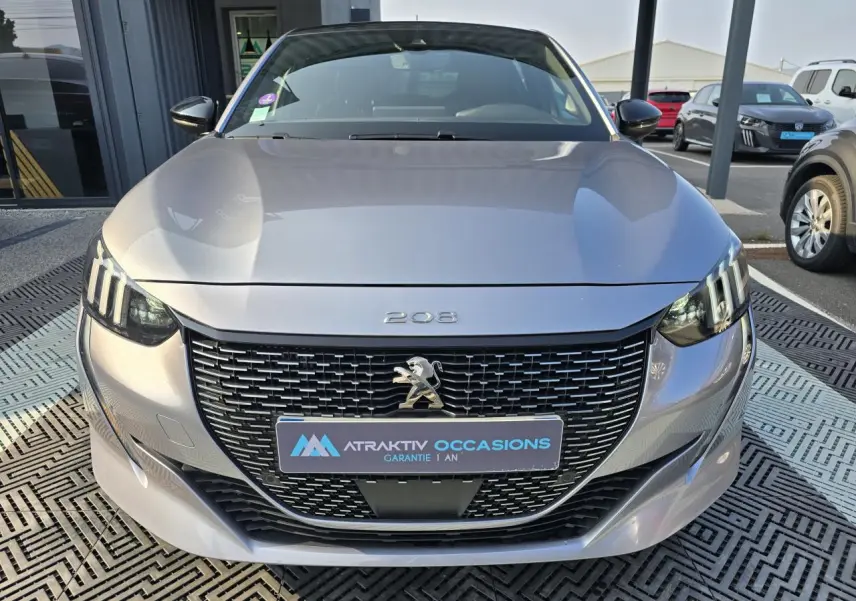 Vue frontale d'une Peugeot 208 grise 2023 avec calandre noire et feux LED à signature 3 griffes.