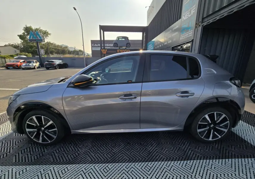 Profil côté gauche d'une Peugeot 208 grise 2023 avec jantes alliage 17'' et toit Black Diamond noir.