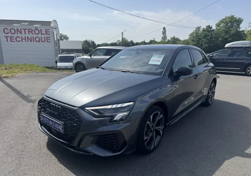 Audi A3 Sportback TDI 2.0 S-Line gris vue 3/4 avant droit, avec calandre noire et jantes sportives distinctives.