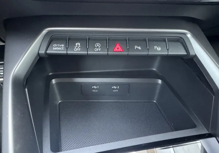 Vue rapprochée de la console centrale noire de l'Audi A3 Sportback TDI 2.0 S-Line 2023 avec boutons de contrôle et ports USB.