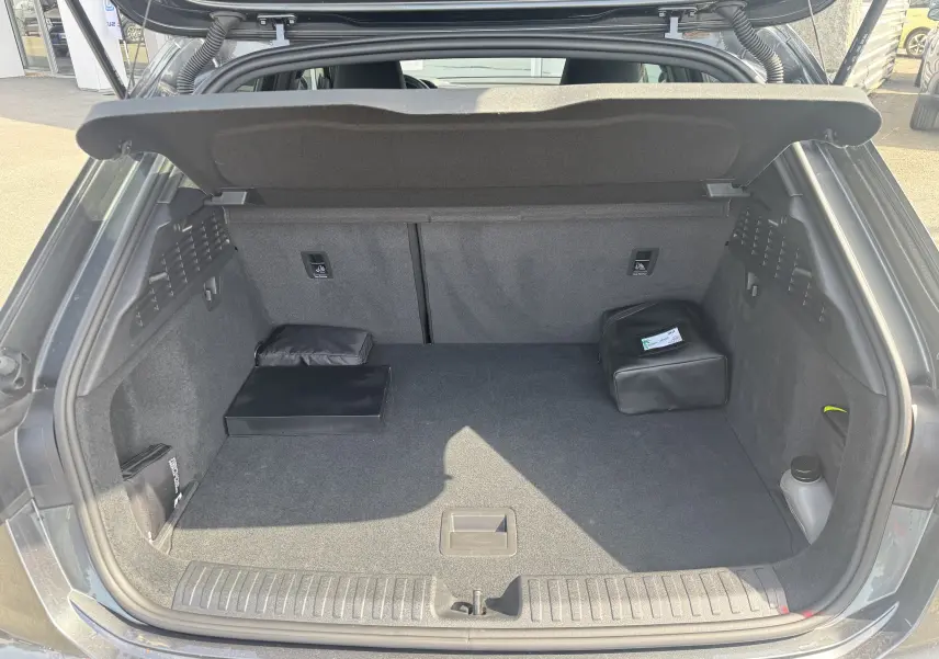 Coffre ouvert vu de l'arrière d'une Audi A3 Sportback gris 2023, avec tapis et quelques accessoires rangés.