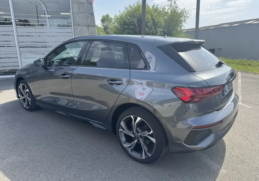 Audi A3 Sportback TDI 2.0 S-Line gris vue 3/4 arrière côté droit, avec jantes alliage et vitres teintées.