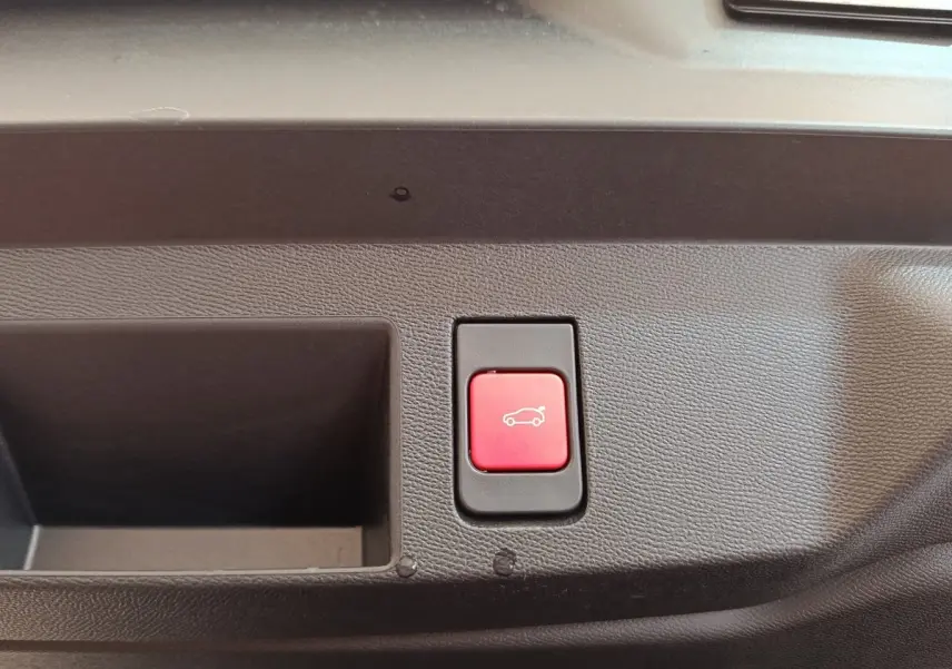 Bouton rouge d'ouverture électrique du coffre sur panneau intérieur d'une Citroën C5 Hybride 2026.